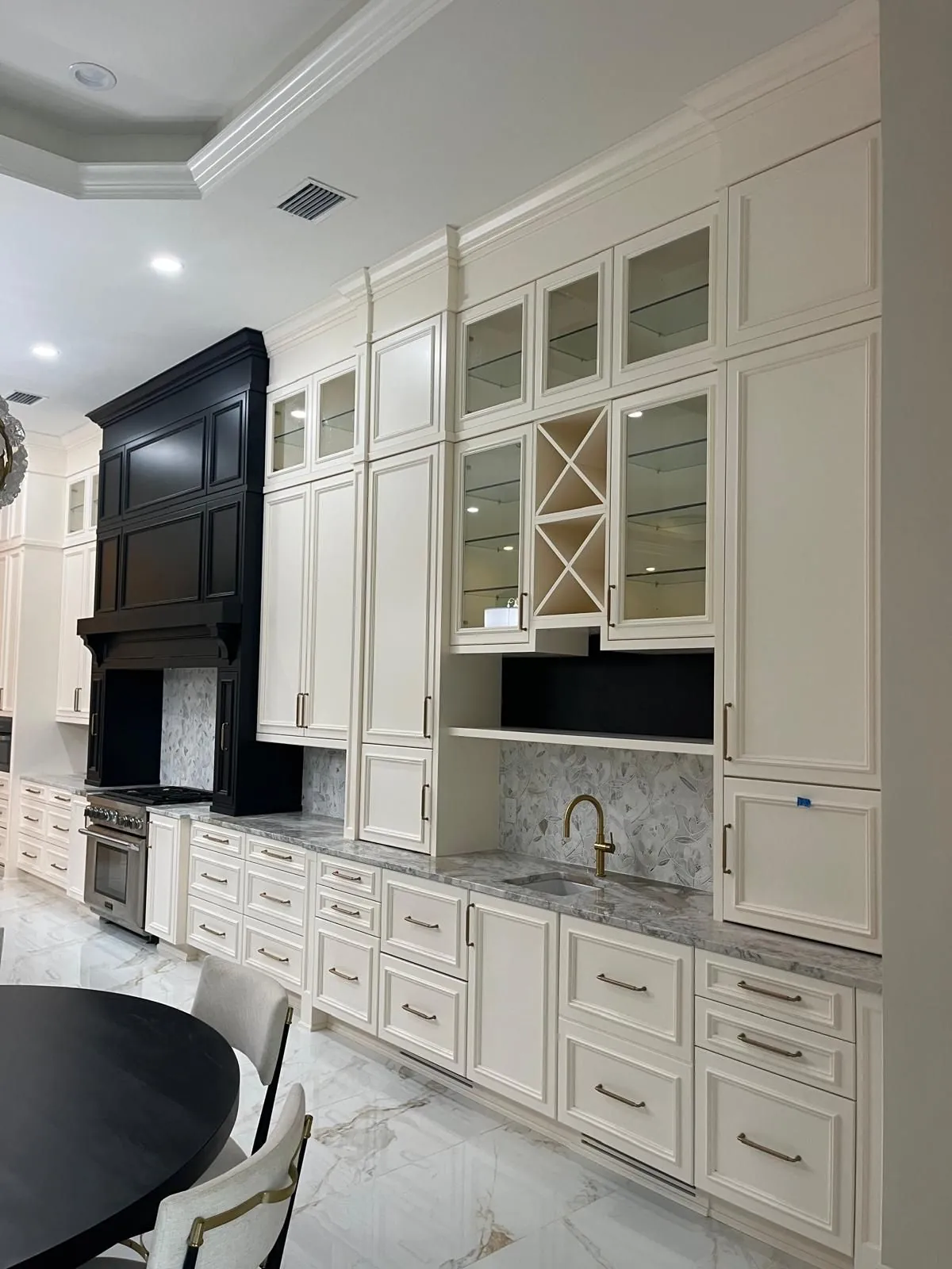 Cream cabinet wall with glass doors, a wine rack and a bar sink