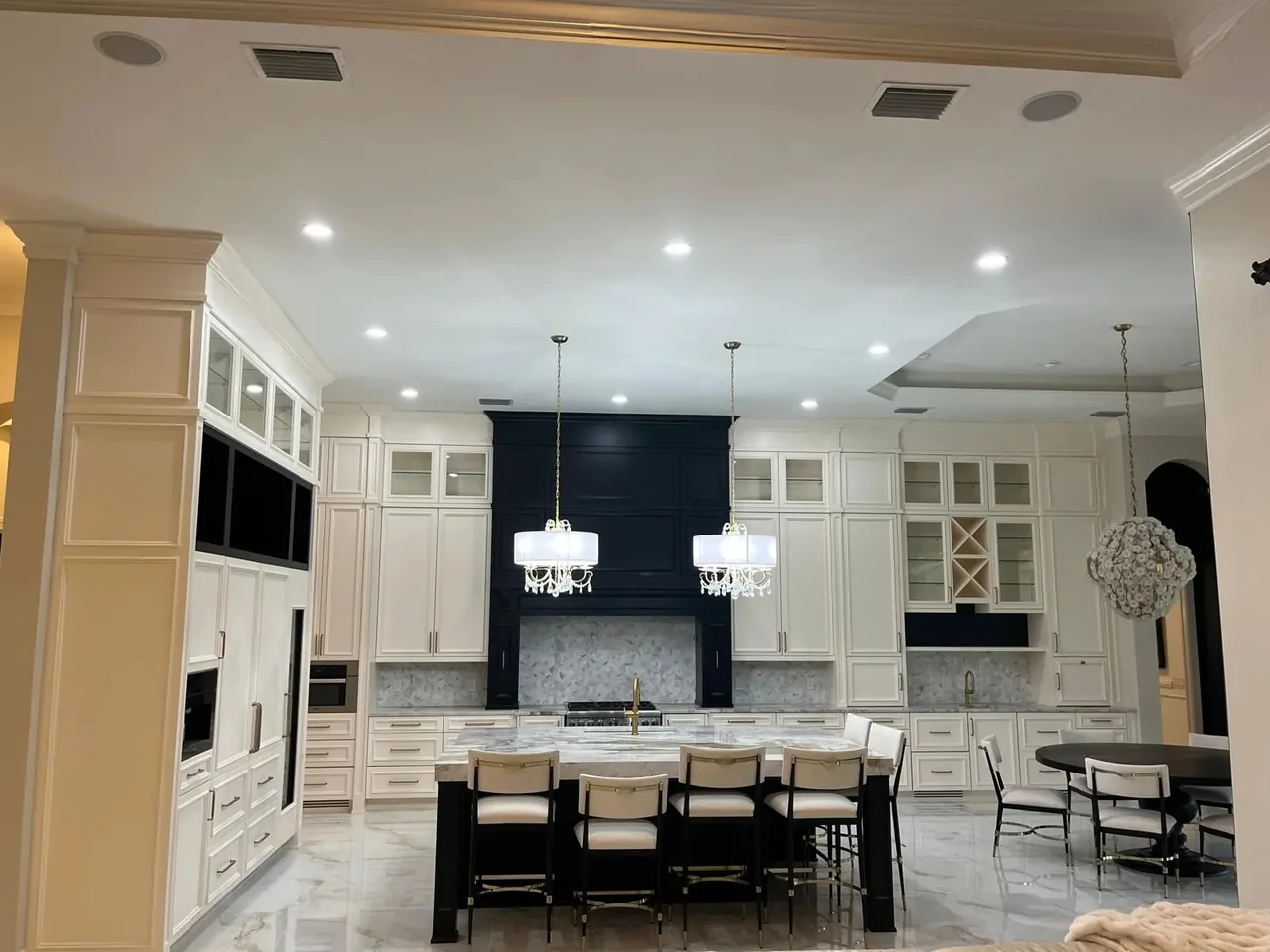 Cocina amplia con gabinetes color crema, campana negra e isla negra