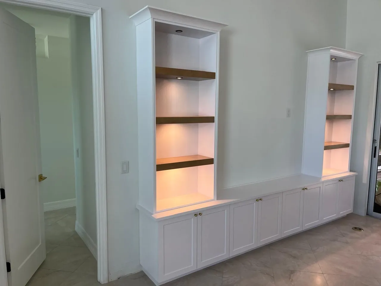 White built-in wall unit with lit wood shelves